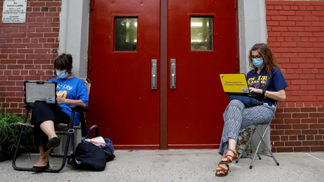 Teachers work outside their school building for safety reasons as they prepare for the delayed start of the school year