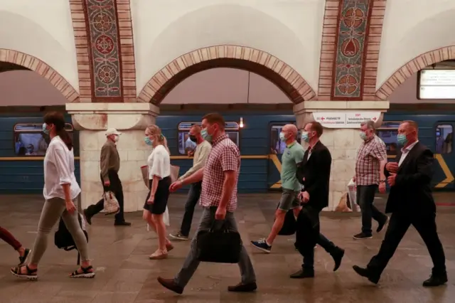 People wearing protective face masks amid the coronavirus disease outbreak walk along a platformn Kyiv, Ukraine