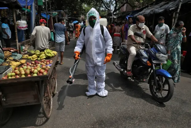 A municipal worker sprays disinfectant to sanitize a street in Kolkata, India