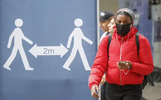 Person in mask and 2m sign