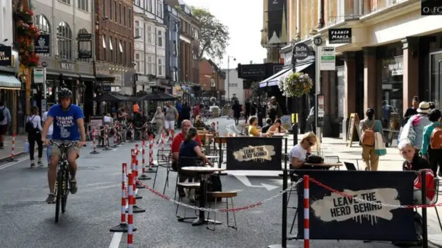 A cyclist riding past a cafe