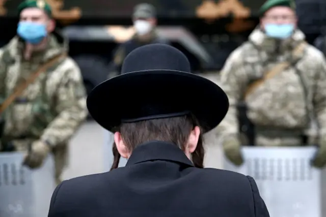 A Hasidic boy stands in front of Ukranian border guards