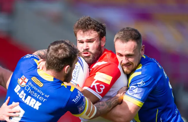 St Helens's Alex Walmsley is tackled by Warrington's Daryl Clark and Ben Currie