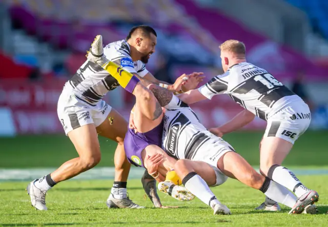 Hull FC Josh Griffin tackles Wigan's Dominic Manfredi with Ligi Sao (left) and Jordan Johnston (right).