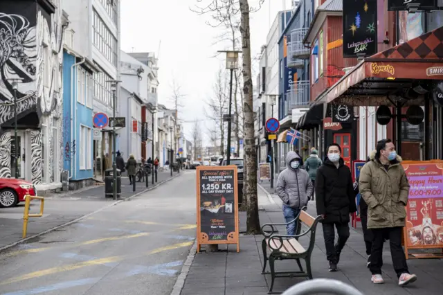 Tourists wearing masks walk down a street in Reykjavik on 3 April 2020
