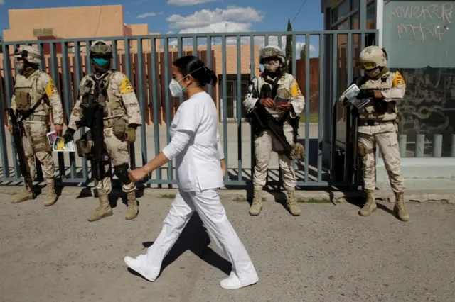 A nurse walks past soldiers in Ciudad Juarez, Mexico