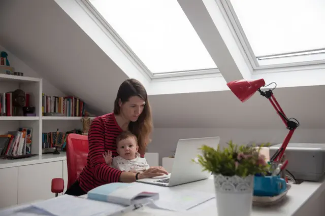 Mother holds her daughter while trying to work from home in Madrid in May 2020