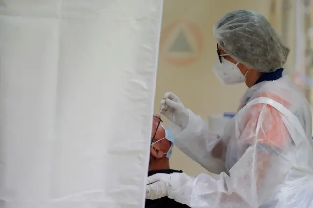 A worker gives a test to a man in France