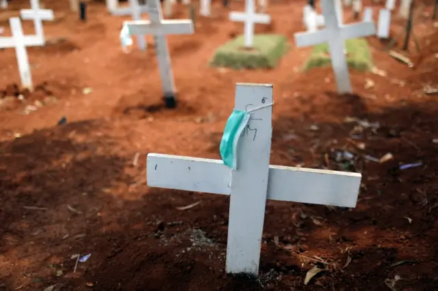 A face mask hangs on a cross at a burial site for coronavirus victims in the Indonesian Jakarta