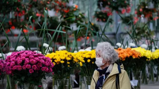 An elderly woman wearing a mask walks in the Botanical Garden of Moscow State University in Russia