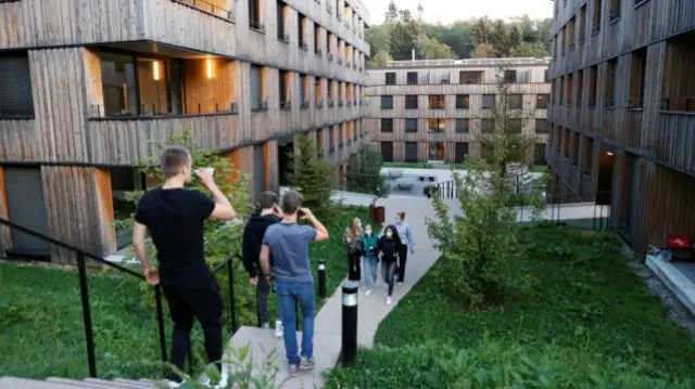 Students walk on the premises of the Ecole Hoteliere de Lausanne after its students were put under quarantine