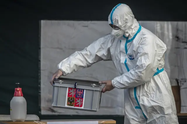 An election committee member wearing protective equipment carries a ballot box at drive-in polling station in Prague, Czech Republic, 30 September 2020.