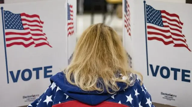 A woman votes in a booth