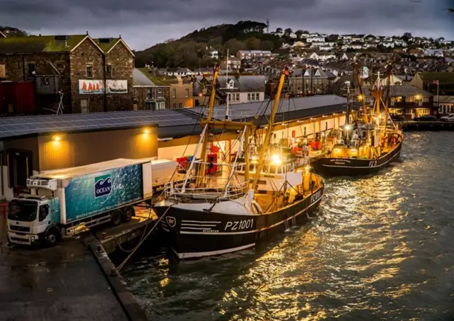 Beam trawlers landing at the fish market at night