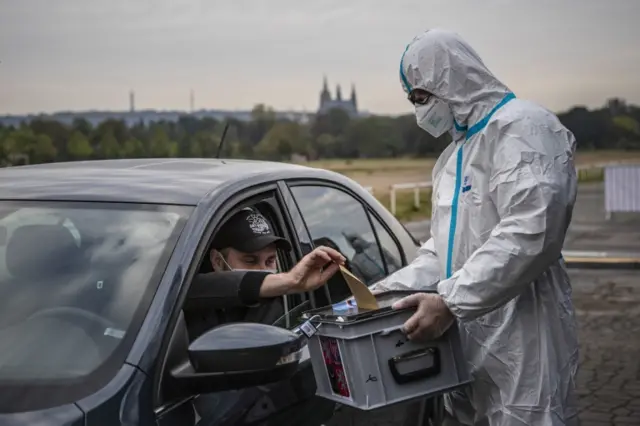 An election committee member holds a ballot box for a voter at drive-in polling station in Prague, Czech Republic, 30 September 2020.