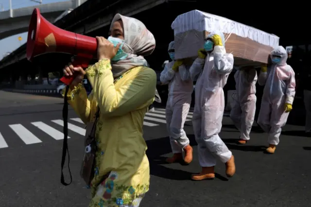 Government workers carry a coffin as a public health message in Jakarta, Indonesia, on 28 August 2020