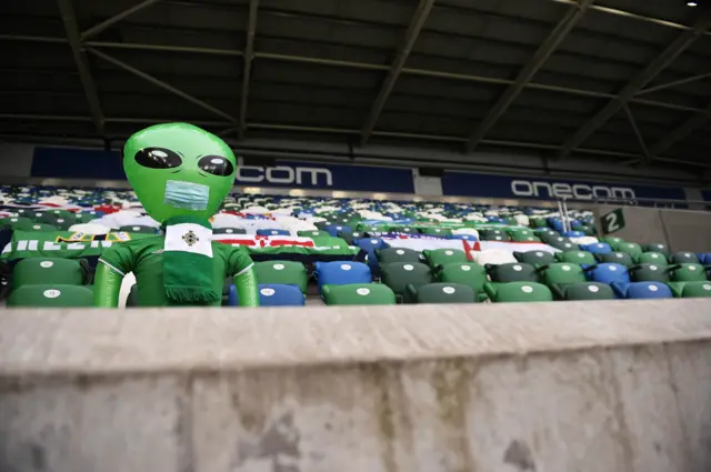 A lone inflatable dressed in Northern Ireland colours occupies an empty stand at Windsor Park