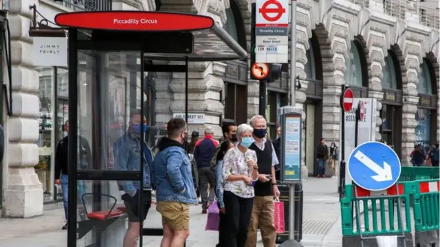 People waiting by a bus stop in London