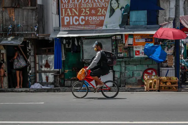 A man wears a face mask and face shield while riding his bicycle in Makati, south of Manila, Philippines, 01 September 2020