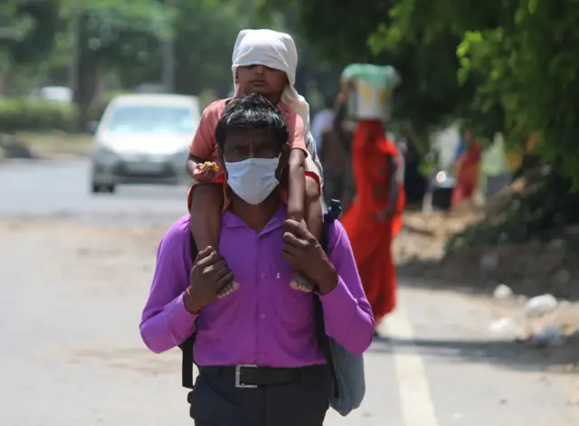 A man and his won are wearing masks and walking down the road.