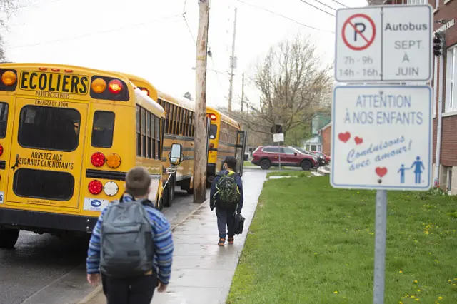 Students wearing protective masks walk to school buses after class in Ormstown, Quebec, Canada, on Monday May 11, 2020