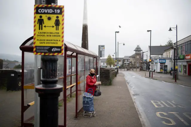 Woman at bus stop in mask