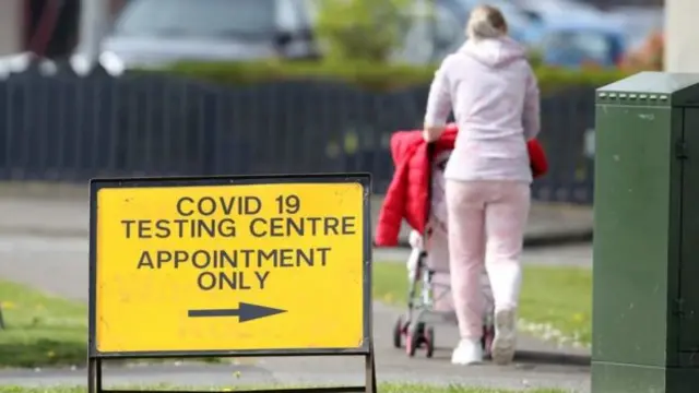 Mother with pram passes a testing sign
