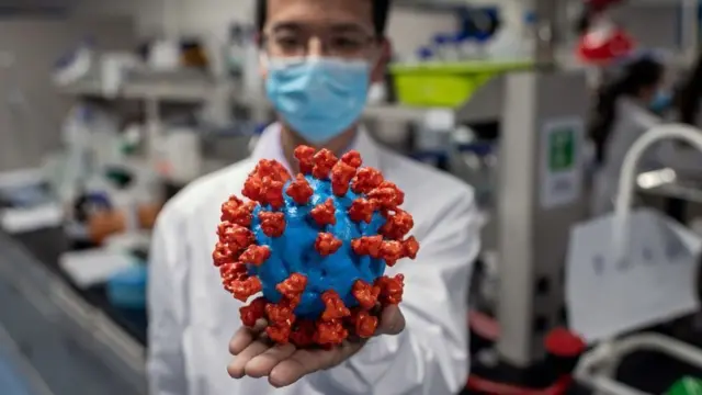 Scientist holds up model of virus