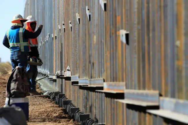 Workers from the Ultimate Concrete construction company speed up their task to finish the metal wall