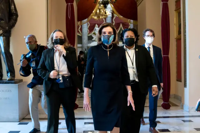 Speaker of the House Nancy Pelosi (D-CA) (C) wears a protective mask while walking to the House Floor at the U.S. Capitol on January 13, 2021