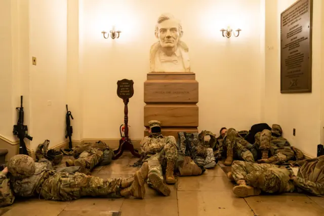 Troops sleep near a bust of Abraham Lincoln