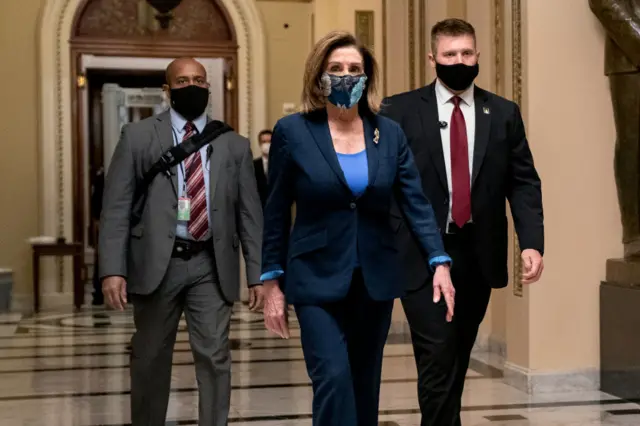 Speaker of the House Nancy Pelosi (D-CA) (C) wears a protective mask while walking to her office from the House Floor at the U.S. Capitol on January 12, 2021