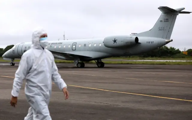 A healthworker walks near a Brazilian Air Force airplane in Manaus before it takes off with COVID-19 patients