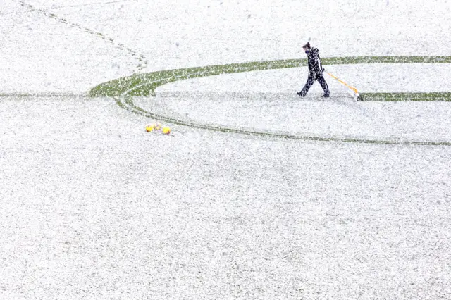 Groundsman removing snow from pitch markings