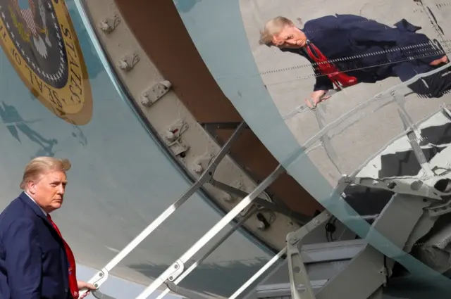 US President Donald Trump is seen reflected while boarding Air Force One at Palm Beach International Airport in West Palm Beach, Florida, on 31 December 2020