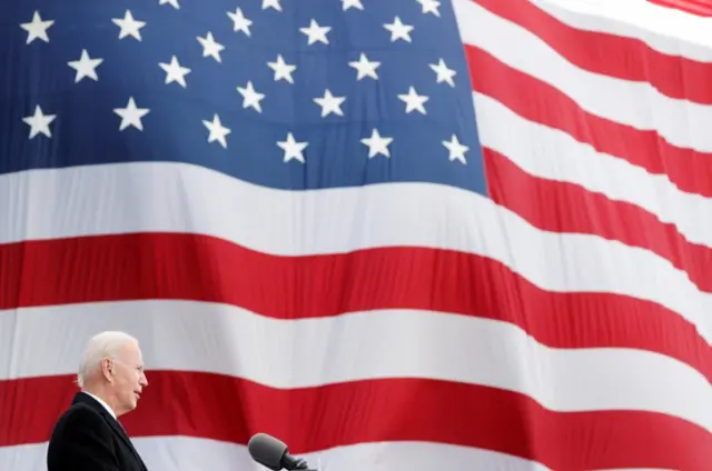 Joe Biden speaks in front of a giant US flag, 19 January