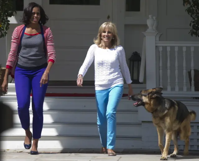 Michelle Obama and Jill Biden walk with the Bidens' dog Champ in 2012