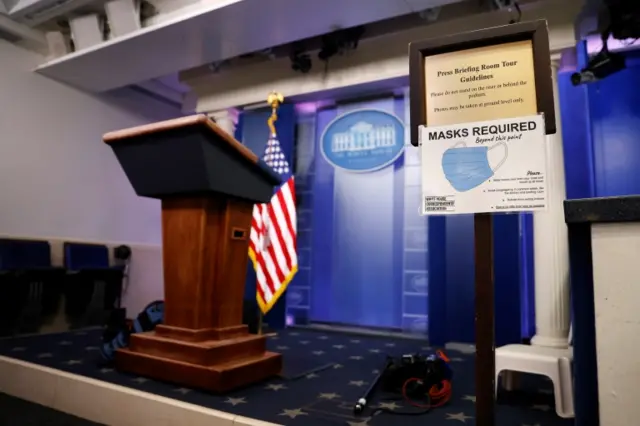 A sign from December tells visitors masks are required in the White House briefing room