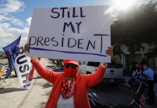 A Trump supporter holds a 'Still my President' sign'