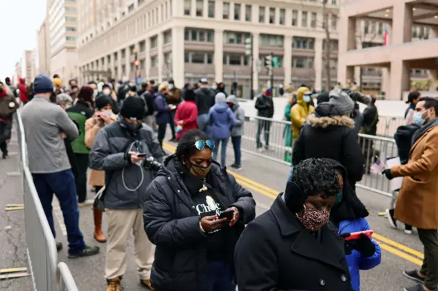 People wait in line to enter a security checkpoint before the start of the inauguration