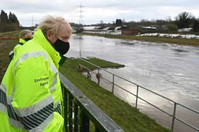 Prime Minister Boris Johnson talks with Environment Agency workers during a visit to a storm basin near the River Mersey in Didsbury, Manchester, to view the flood defences put in place for Storm Christoph