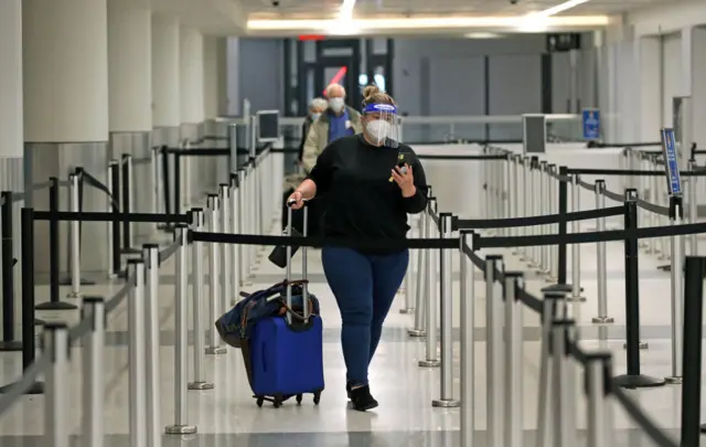 : A passenger wearing a facial shield and mask walks to her flight with no line at Terminal B at Boston Logan International Airport in Boston on Nov. 23, 2020.