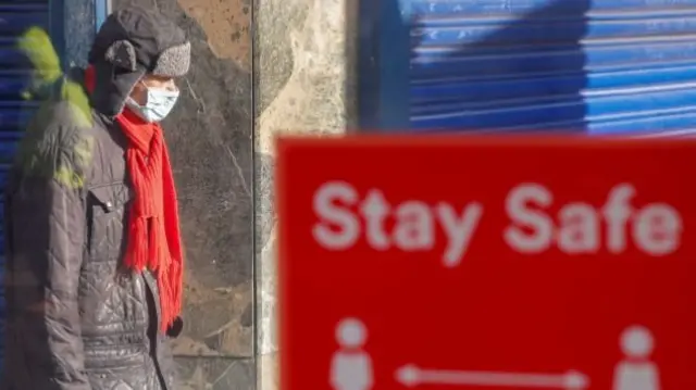 Man in mask and 2m sign