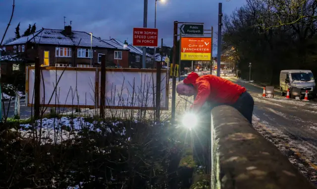 A council worker in Didsbury, Manchester, checks a bridge over the River Mersey for damage after heavy rainfall