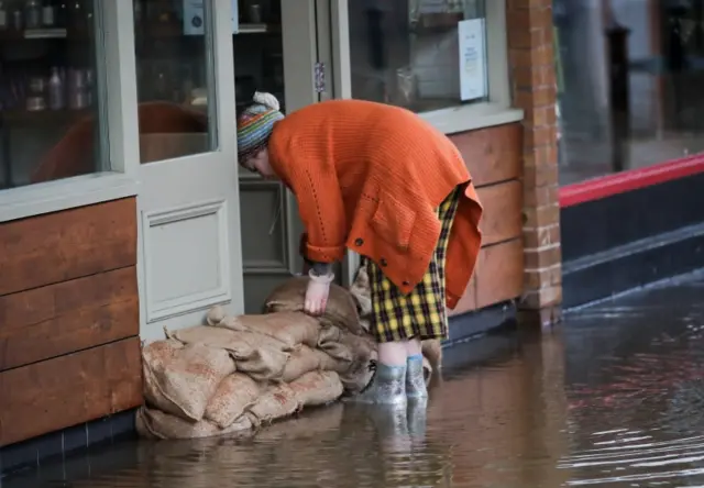 Woman stacking sandbags in Northwich