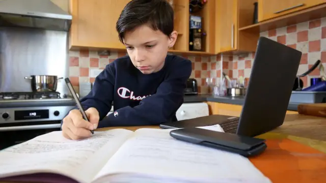 A young boy doing school work in a kitchen