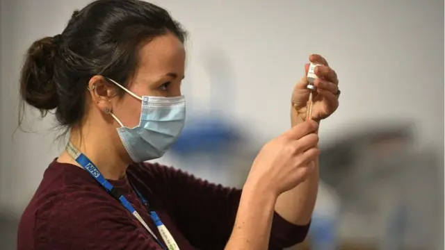 A NHS staff member with a vaccine dose