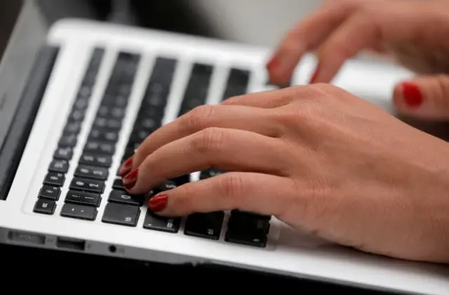 A person types on a laptop computer