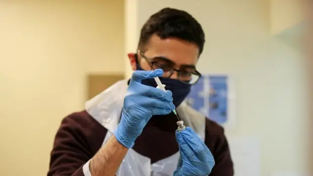 A healthcare worker prepares a vaccine