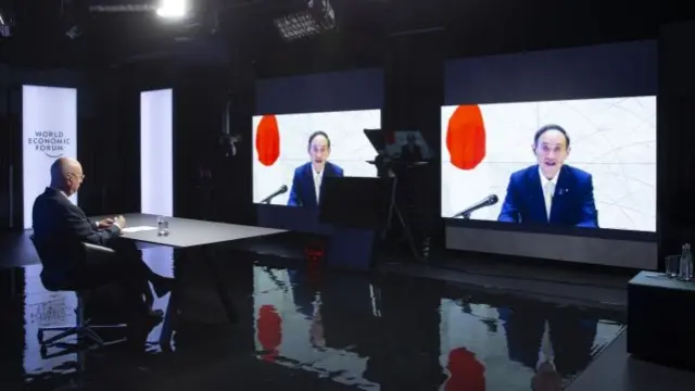 Klaus Schwab (L), founder and Executive Chairman of the World Economic Forum (WEF), listens to Japanese Prime Minister Yoshihide Suga displayed on screens during a video conference at the Davos Agenda, in Cologny near Geneva, Switzerland, on 29 January 2021